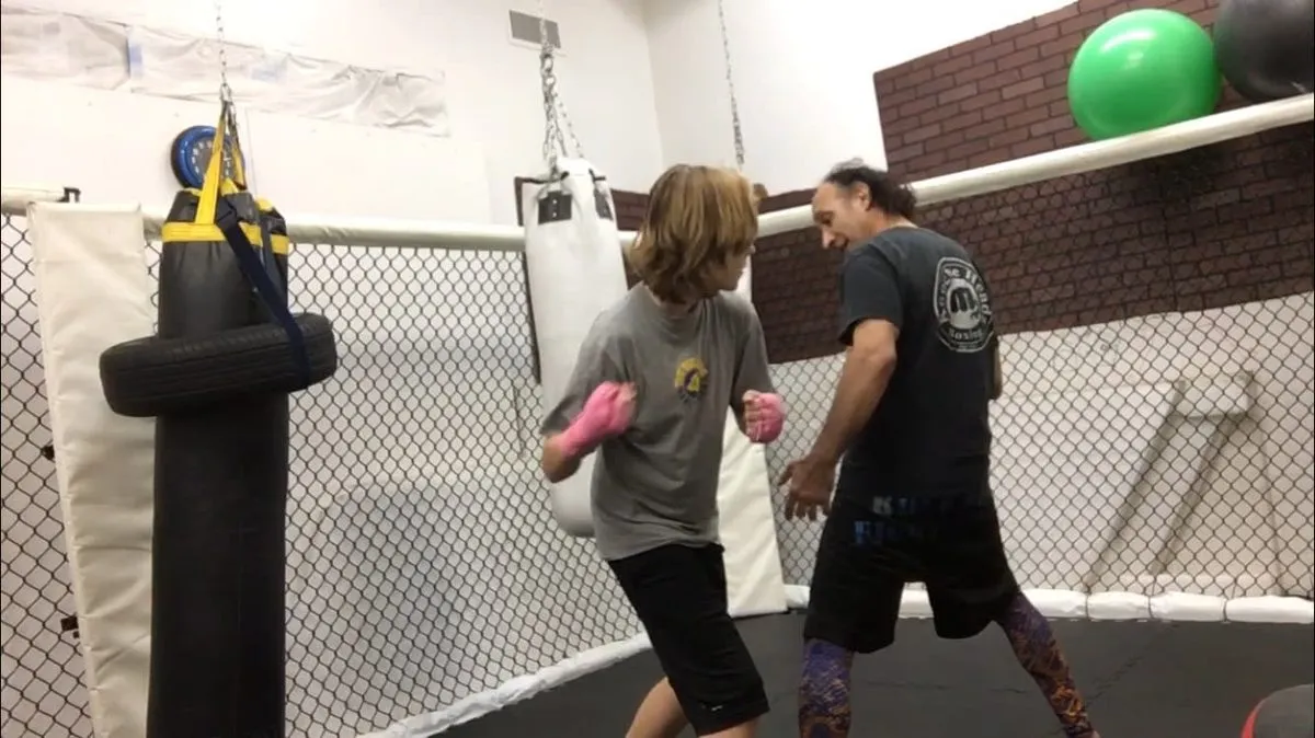Coach Rex Pena teaching a young student to slip a punch inside the hexagon cage