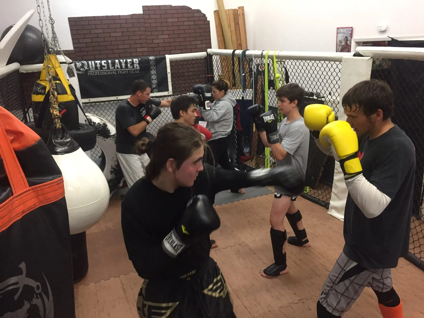 Kickboxing pairs training inside the hexagon cage beside the heavy bags at the Ventura gym