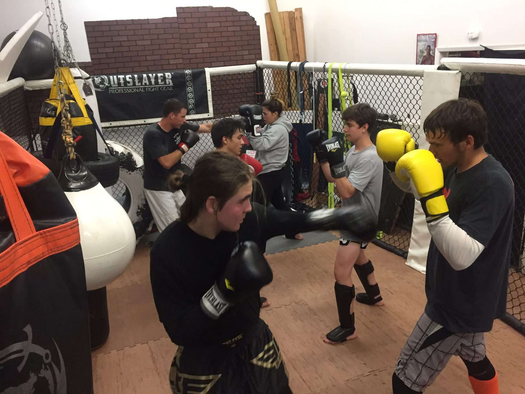 Students drilling kicks and pads inside the hexagon cage at Rock N Roll Fight Company