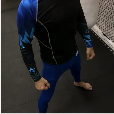 Black rash guard with blue lightning-bolt sleeves and royal blue leggings on the mats